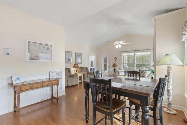 Combined dining and living room with wood floors and ceiling fan at beach retreat