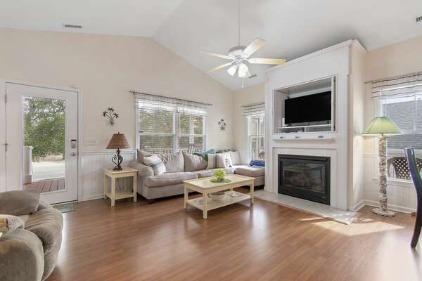 Spacious living room with mounted TV, fireplace, and sectional couch at Old Ferry Coastal Retreat