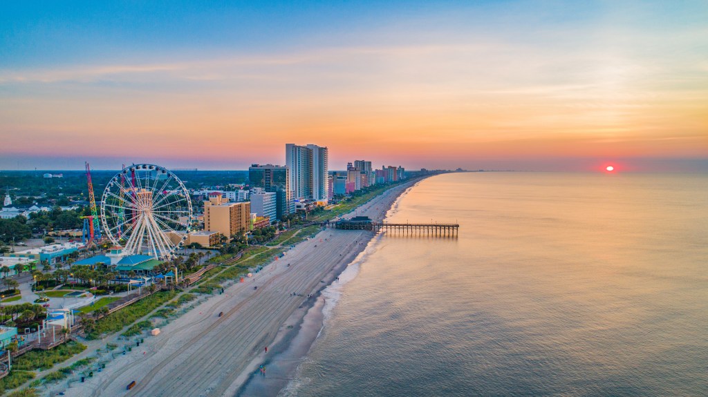 Aerial view of Myrtle Beach boardwalk, Ferris wheel, and oceanfront skyline at sunset