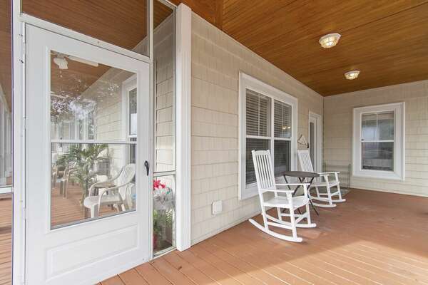 Covered porch at Old Ferry Coastal Retreat with white rocking chairs and warm wood ceiling, perfect for morning coffee