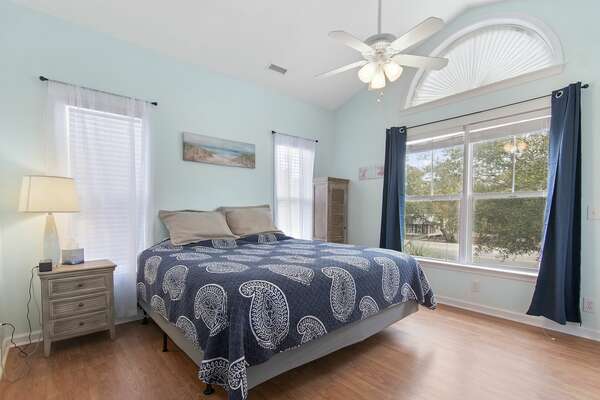 Second bedroom with vaulted ceiling, large window, and blue bedding at Old Ferry Coastal Retreat