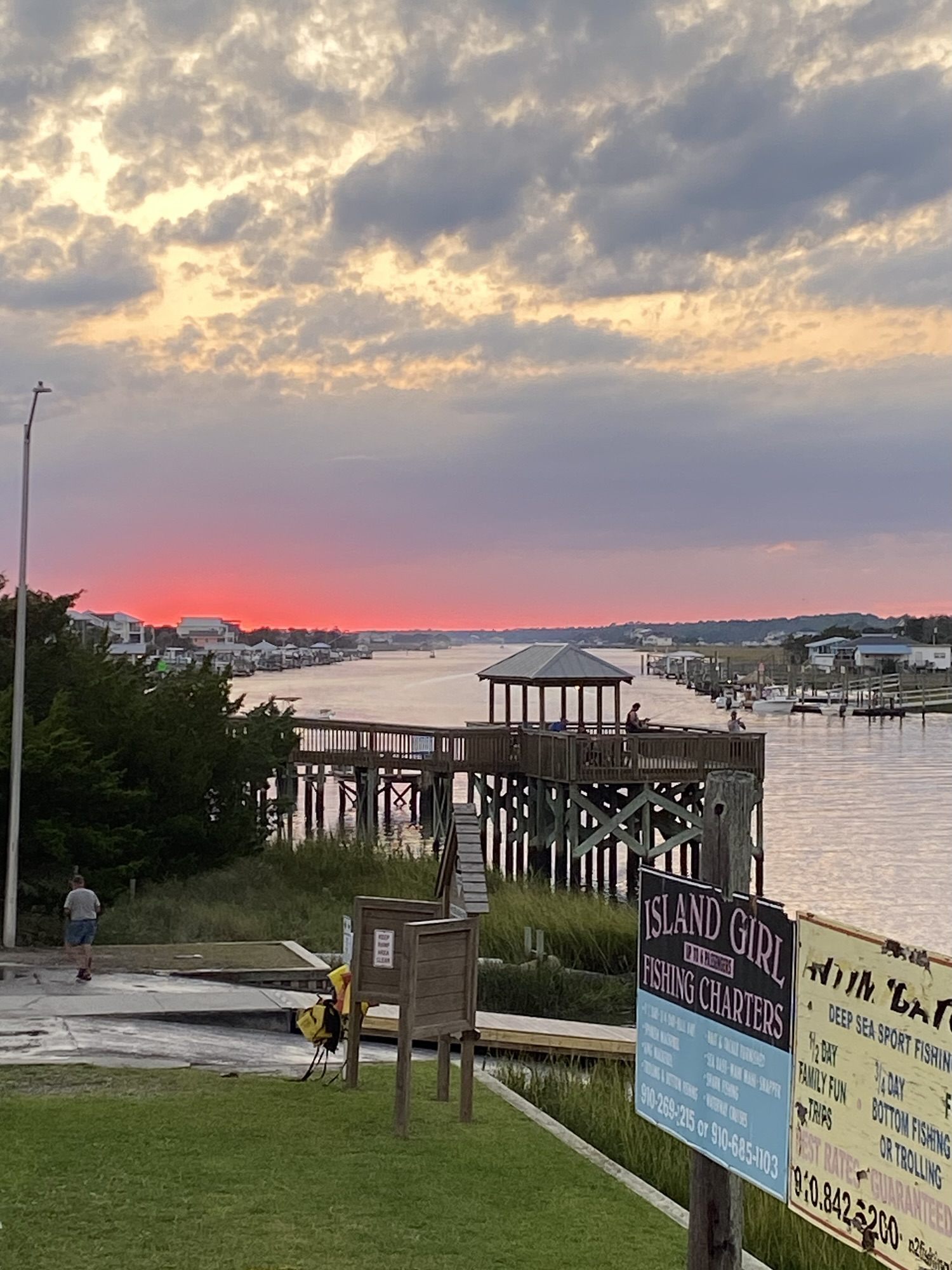 Palm trees and boardwalk lit up at night in Holden Beach