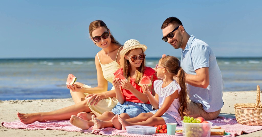 Family having a beach picnic with watermelon near Holden Beach