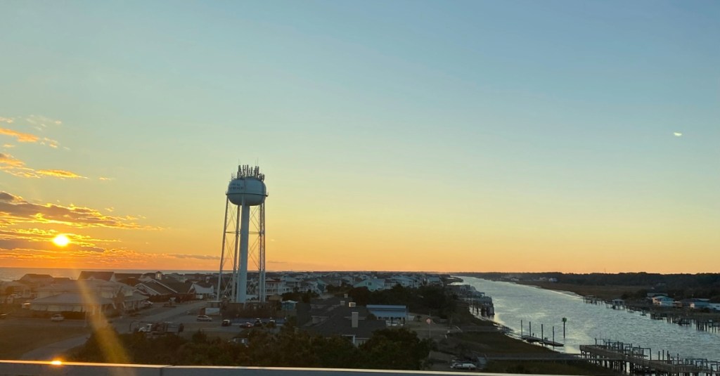 Sunset view from the bridge over Holden Beach with water tower in background